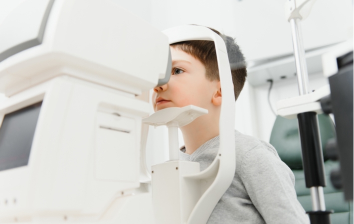 A young boy getting an eye exam from an eye doctor.