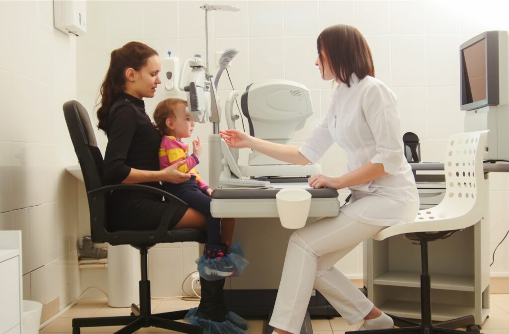 A young child sitting on their mother's lap while an optometrist completes their first eye exam