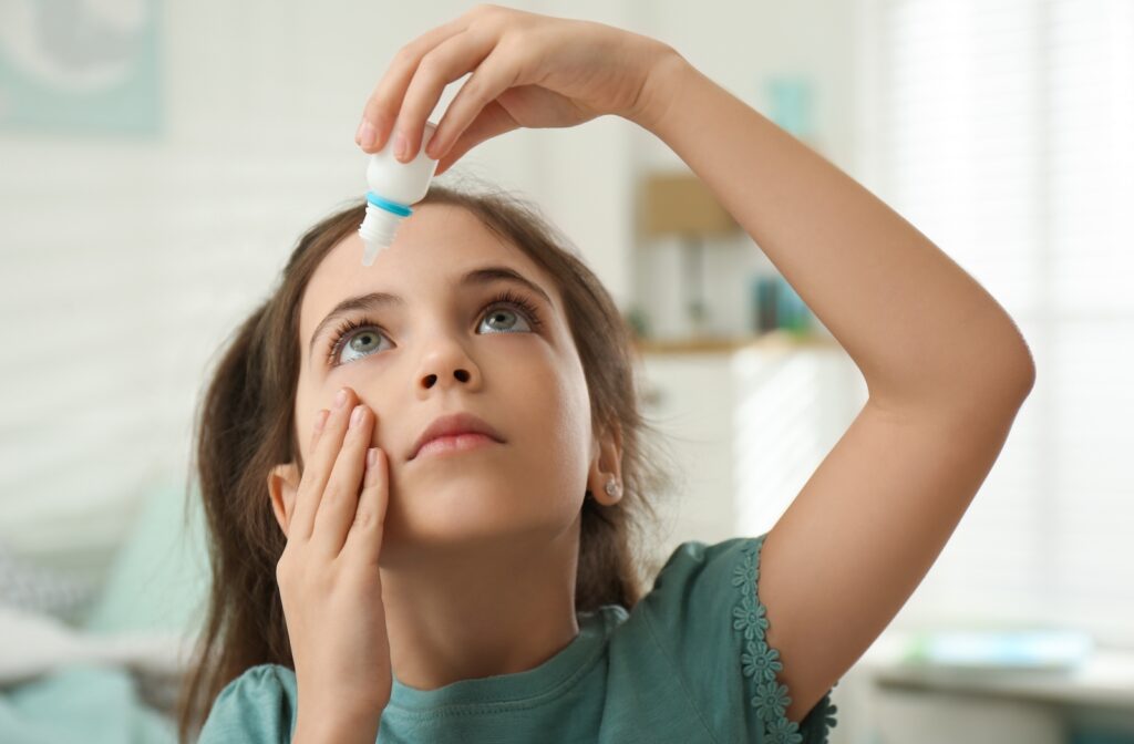A young girl using eye drops into her right eye