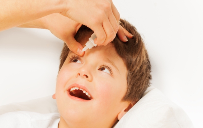 A parent dropping eye drops into a child's eyes