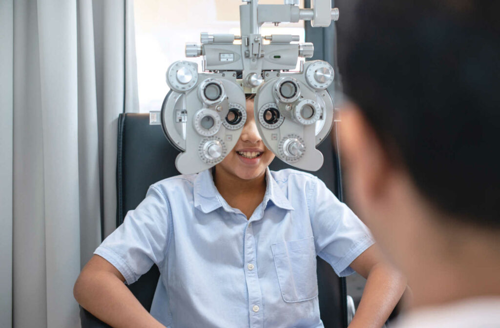 A young boy looking through a phoropter during a children's eye exam