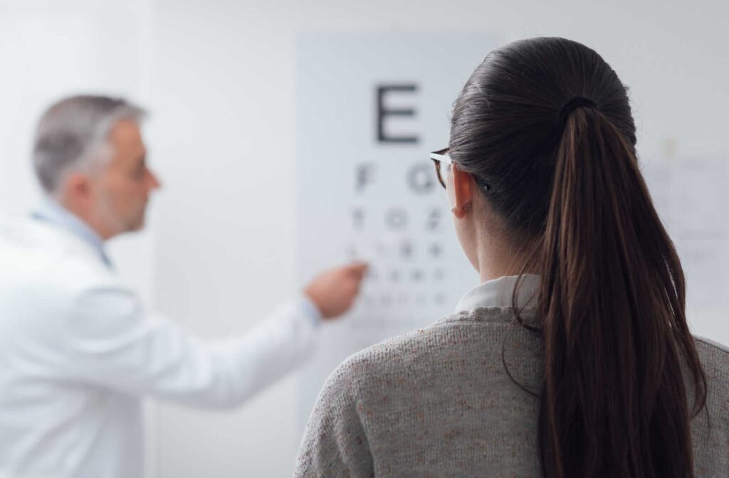 A woman reading an eye chart during an eye exam to test her visual acuity