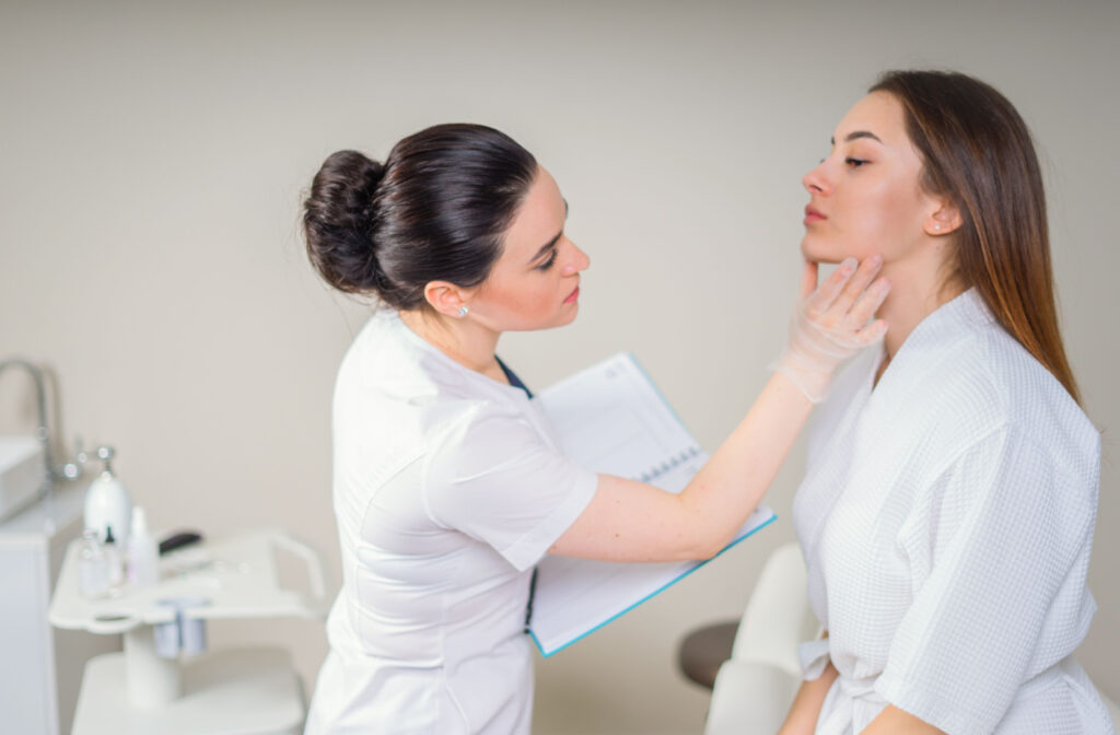 A female skincare professional is examining the face of a female patient.