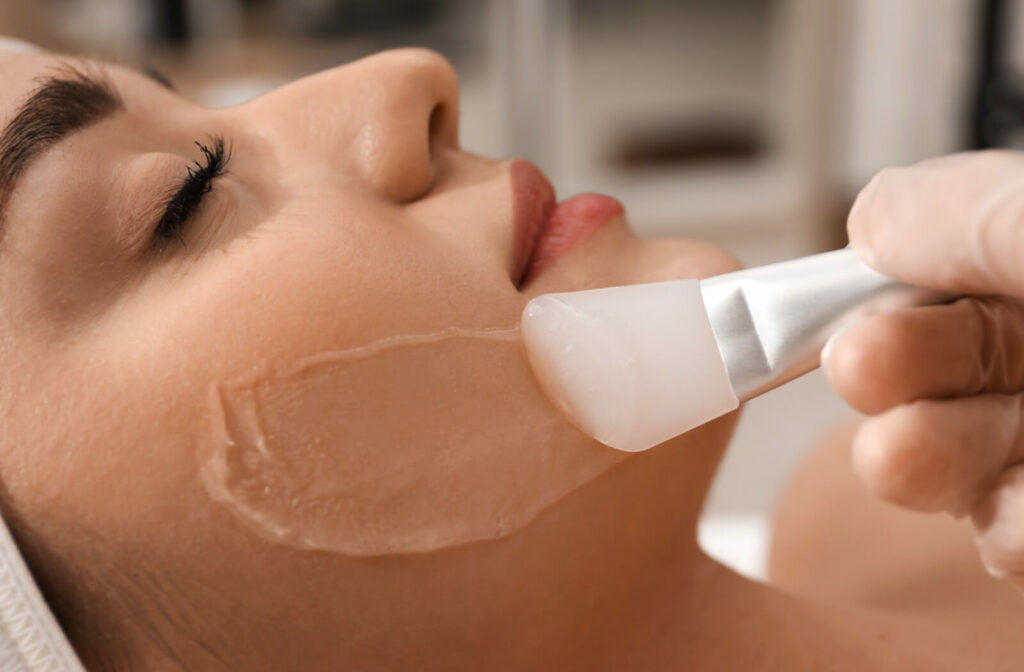 A close-up face of a woman receiving a chemical peel from her aesthetician.