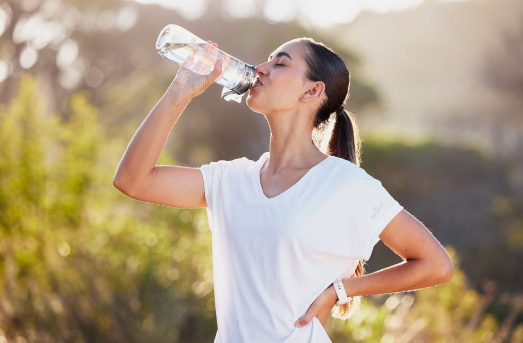 A woman drinking a bottle of water outdoors.