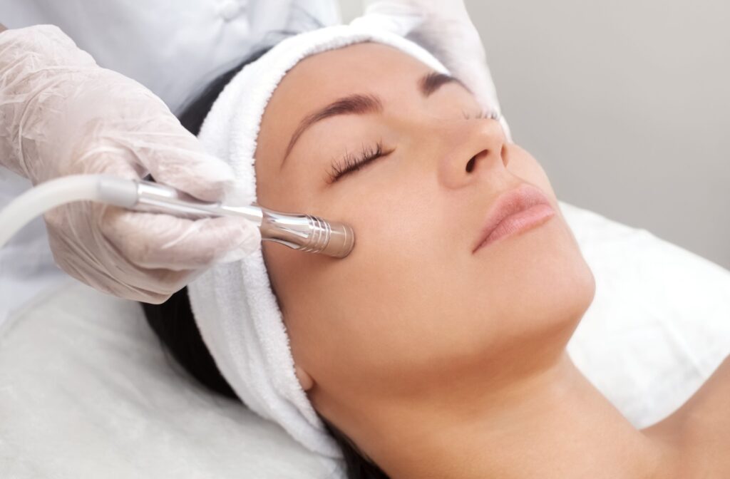 A young woman with her eyes closed is undergoing microdermabrasion treatment.