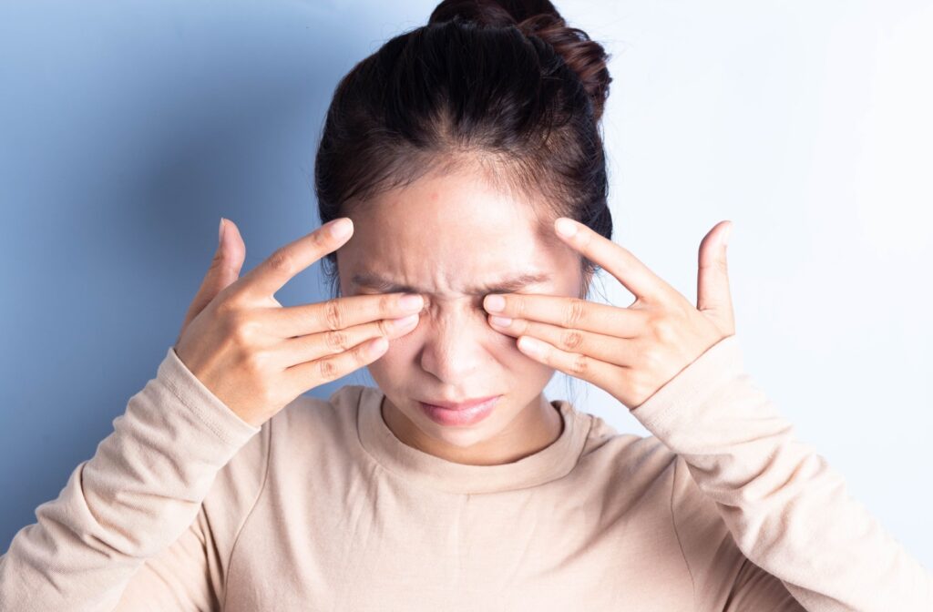 A woman rubbing her eyes with both hands in discomfort due to her eye infection.