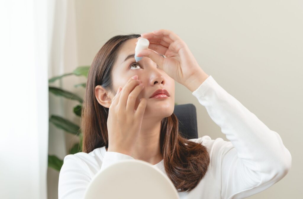 A young adult using eyedrops indoors to prevent blurry vision due to their allergies.