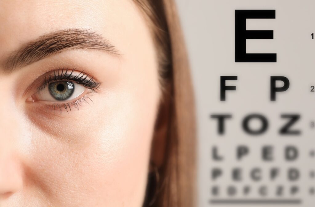 A close-up of a woman with an eye chart in the background.