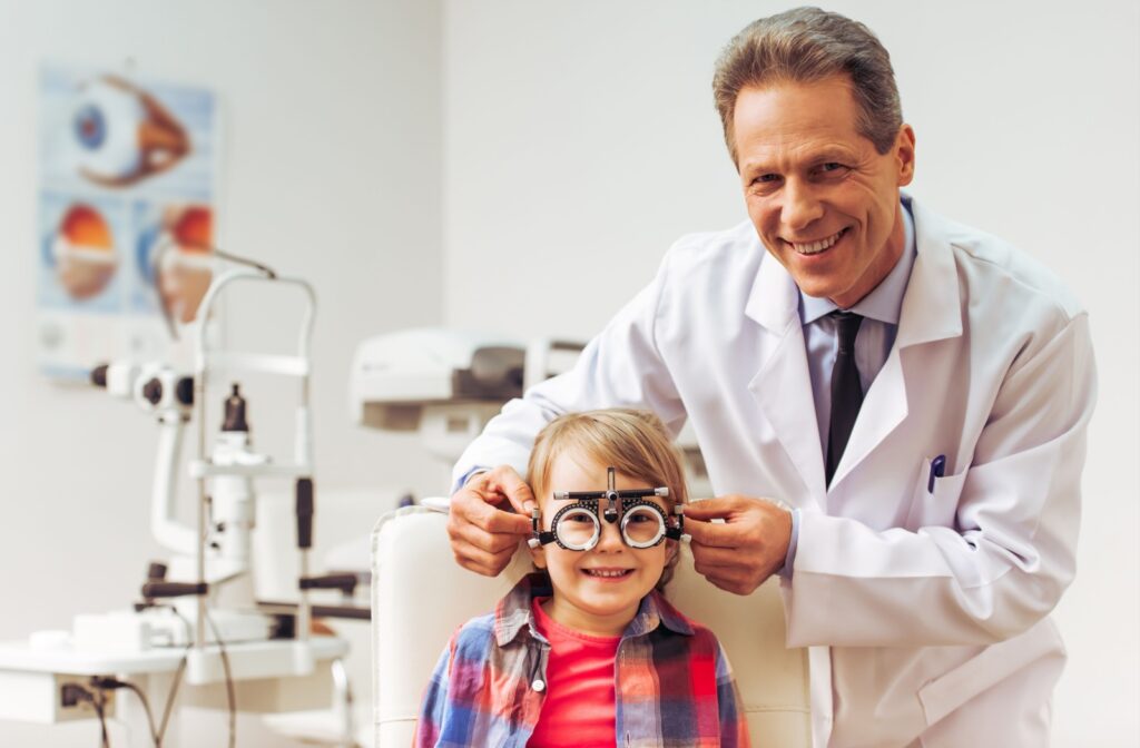 An optometrist fits a young child for glasses during a children's eye exam.