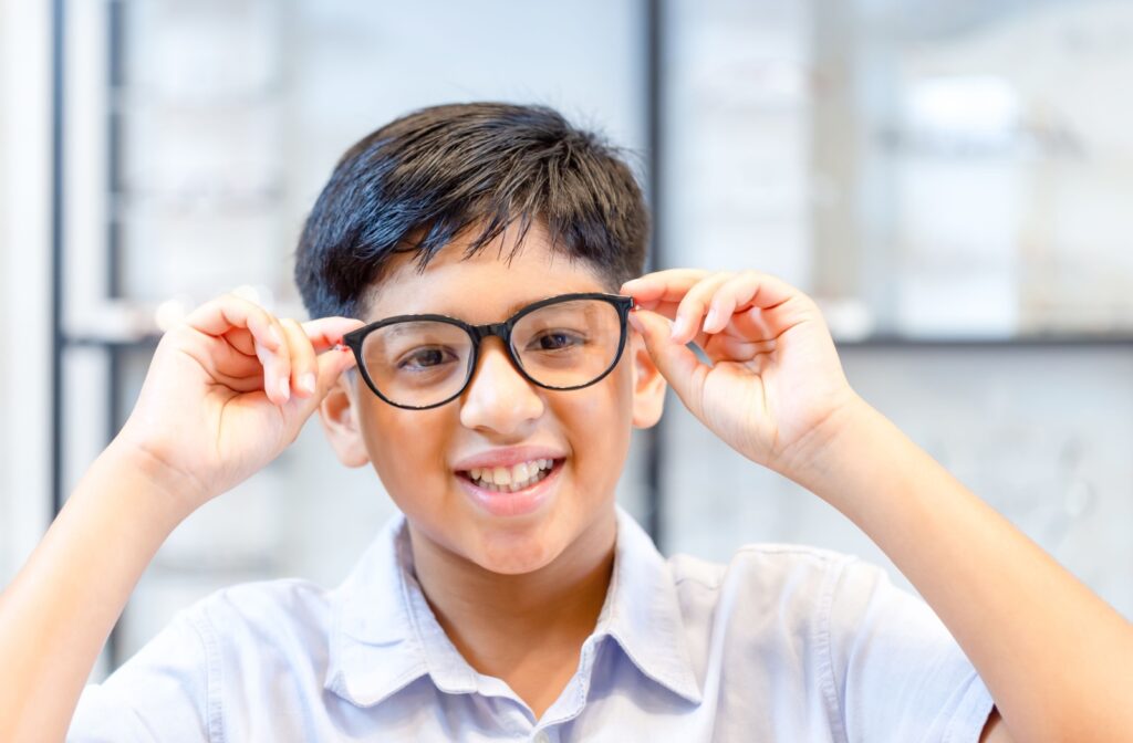 A child holding up a pair of glasses they are trying on