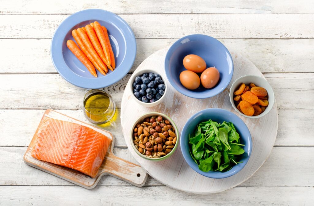 an array of foods high in omega 3 such as eggs, fish, carrots, and spinach.