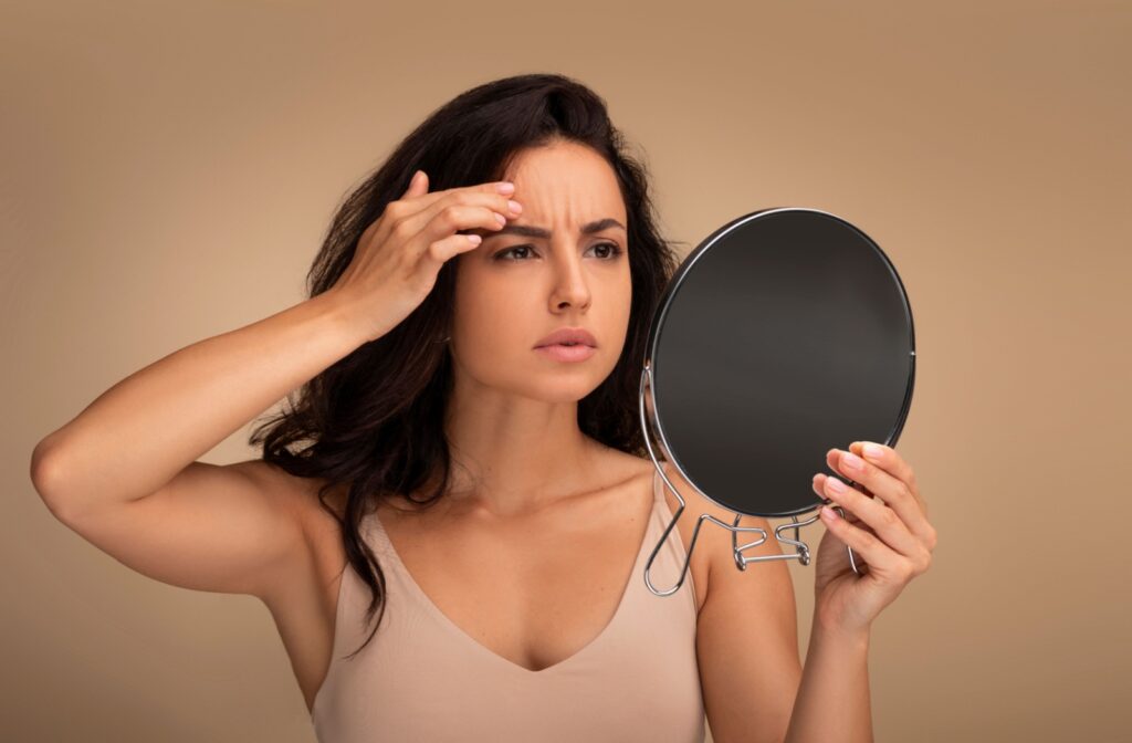 A person looking at their forehead wrinkles in a mirror