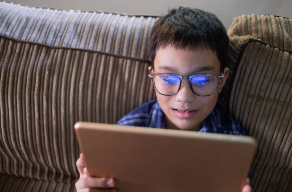 A young child wearing glasses using an ipad